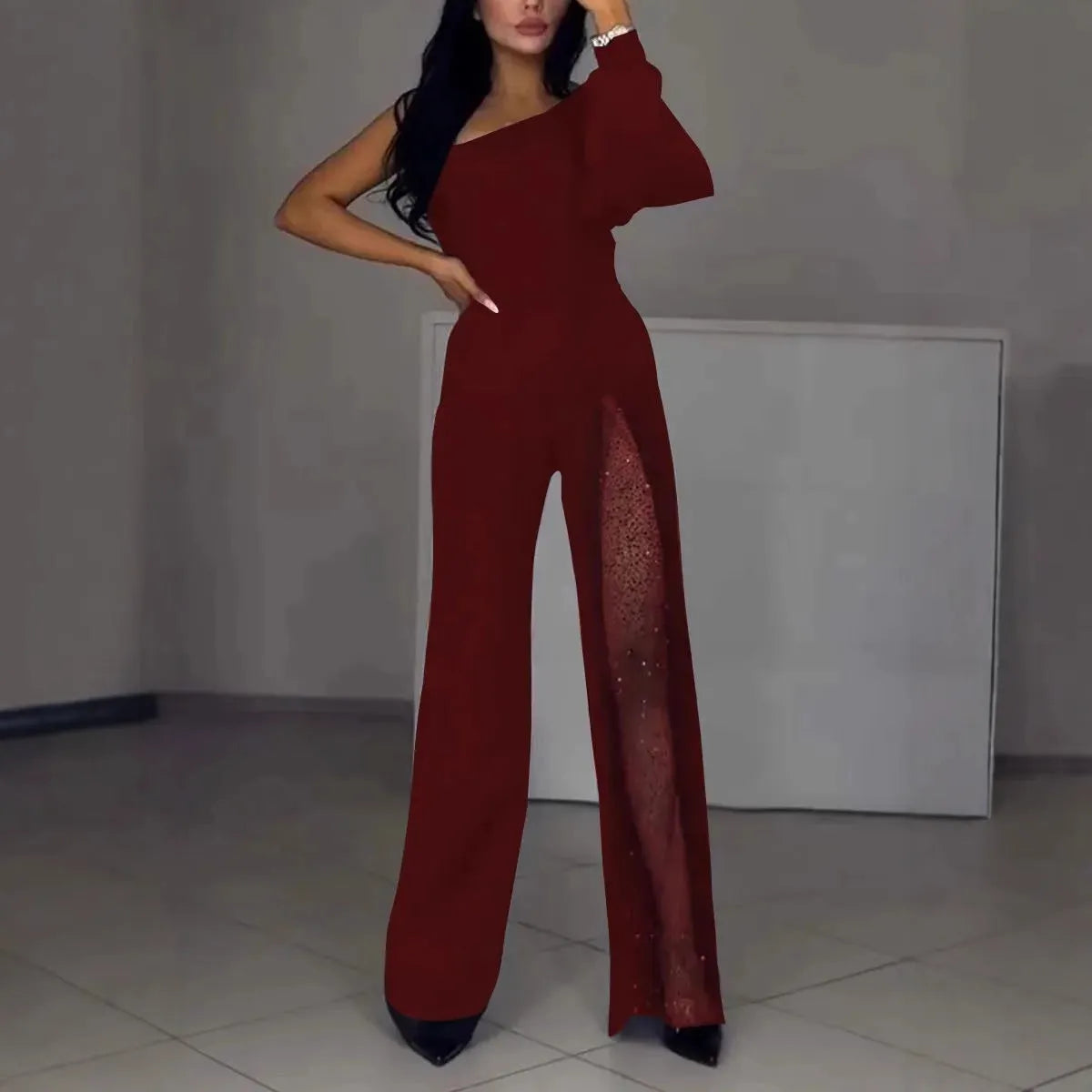 Women's black oblique shoulder jumpsuit with a high leg slit and long sleeves.