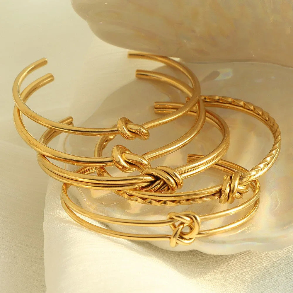 Adjustable stainless steel women's bracelet with gold plating and a double-layer knotted C-shape design.