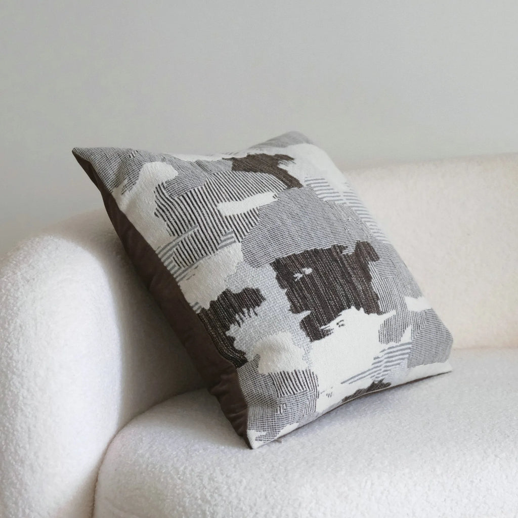 Coffee brown striped mid-century modern lumbar cushion on a grey sofa.