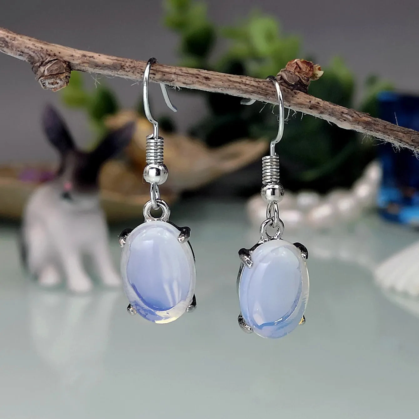A pair of retro drop-shaped earrings with an opal moonstone colour and elliptical decorative elements.