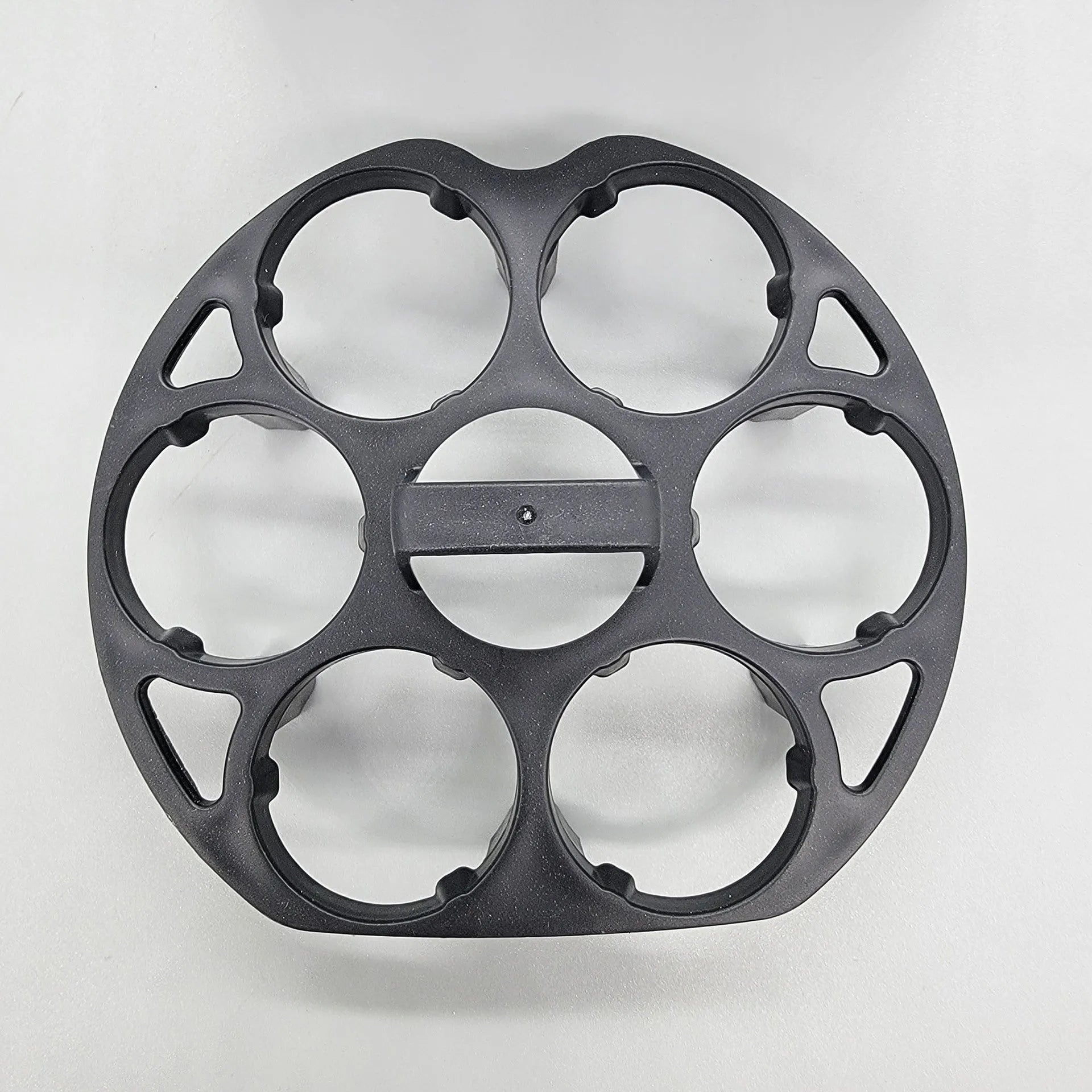 Black plastic egg holder rack for a cooking machine on a kitchen countertop.
