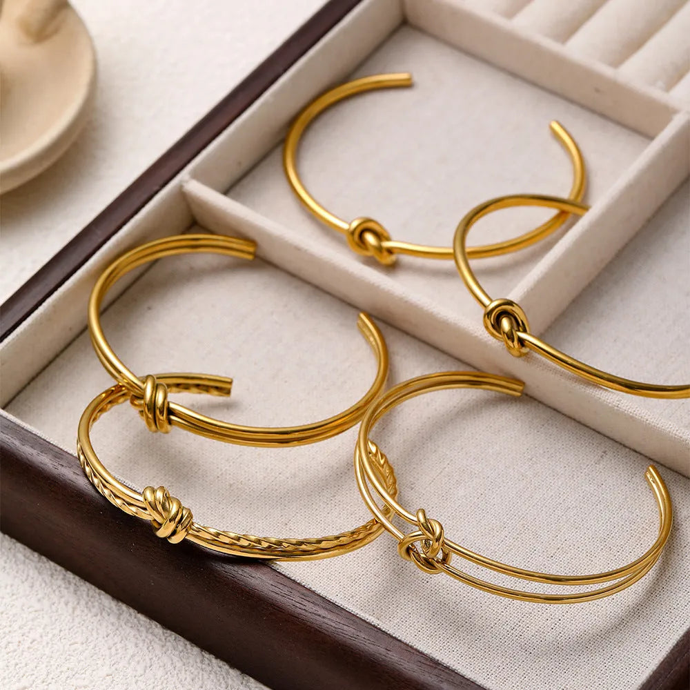 Adjustable stainless steel women's bracelet with gold plating and a double-layer knotted C-shape design.