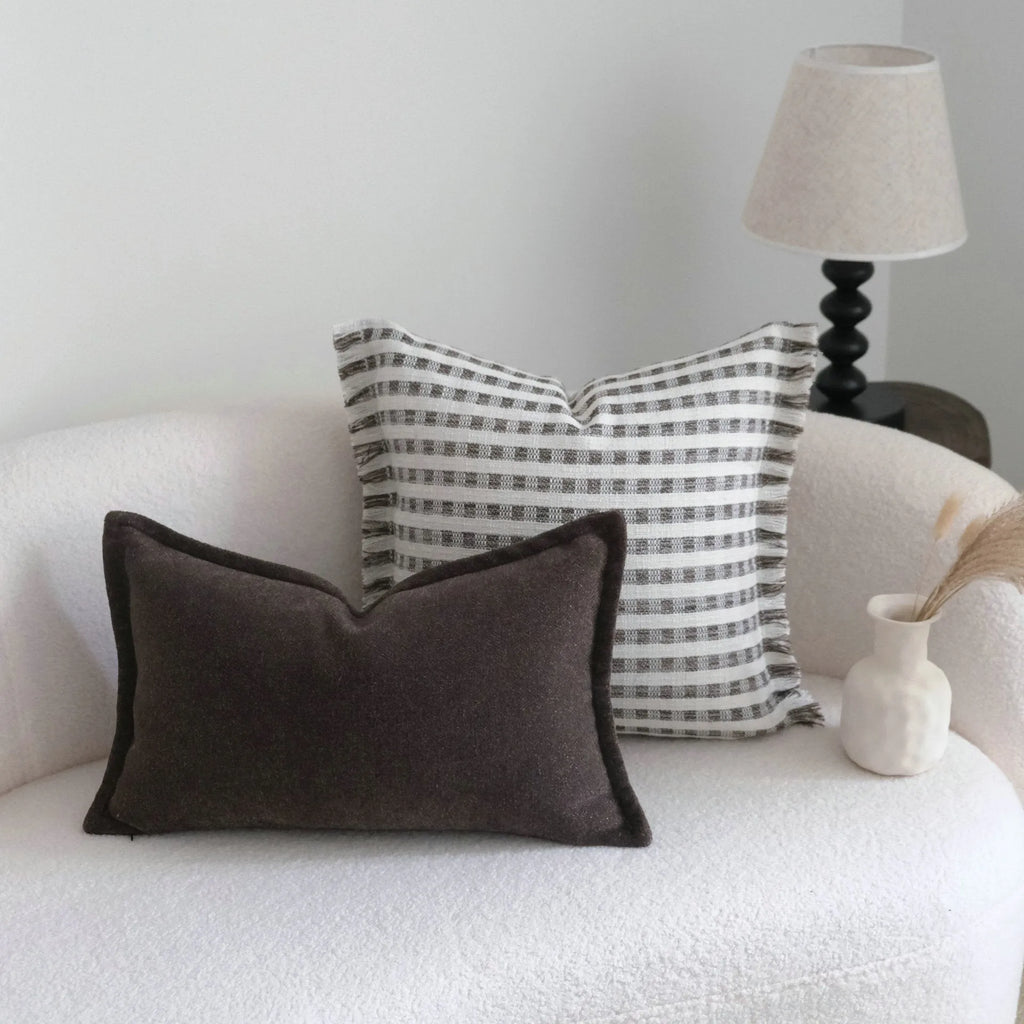 Coffee brown striped mid-century modern lumbar cushion on a grey sofa.
