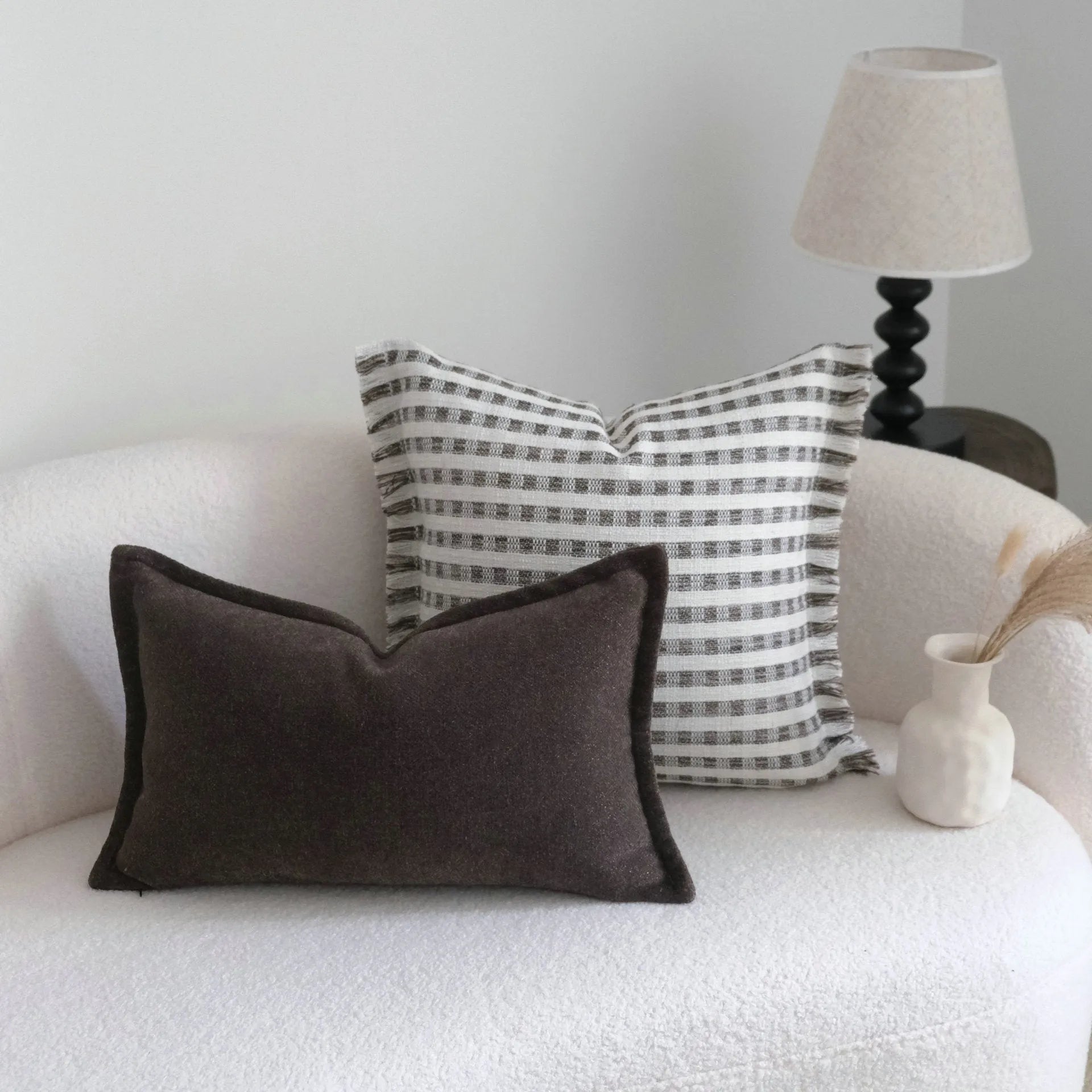 Coffee brown striped mid-century modern lumbar cushion on a grey sofa.