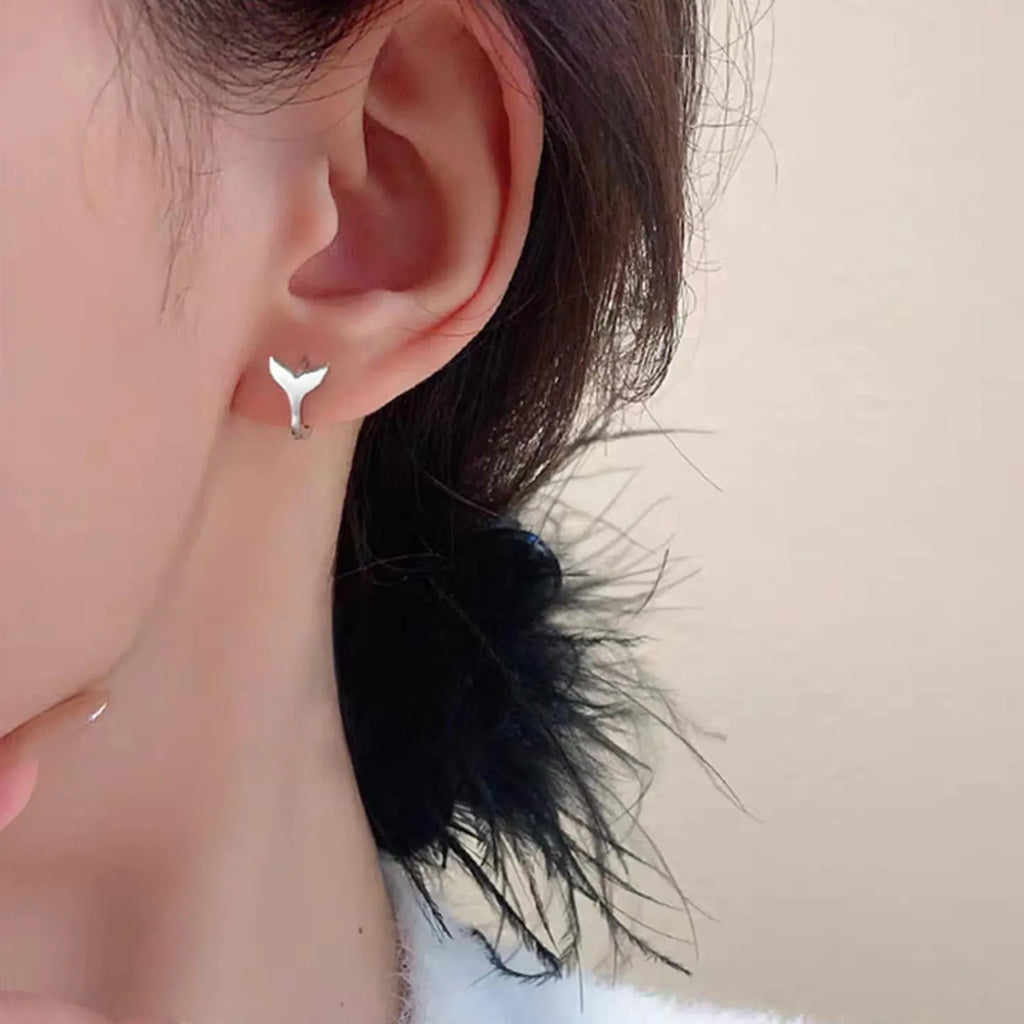 A pair of simple women's fishtail earrings in electroplated copper, shown in white gold colour.