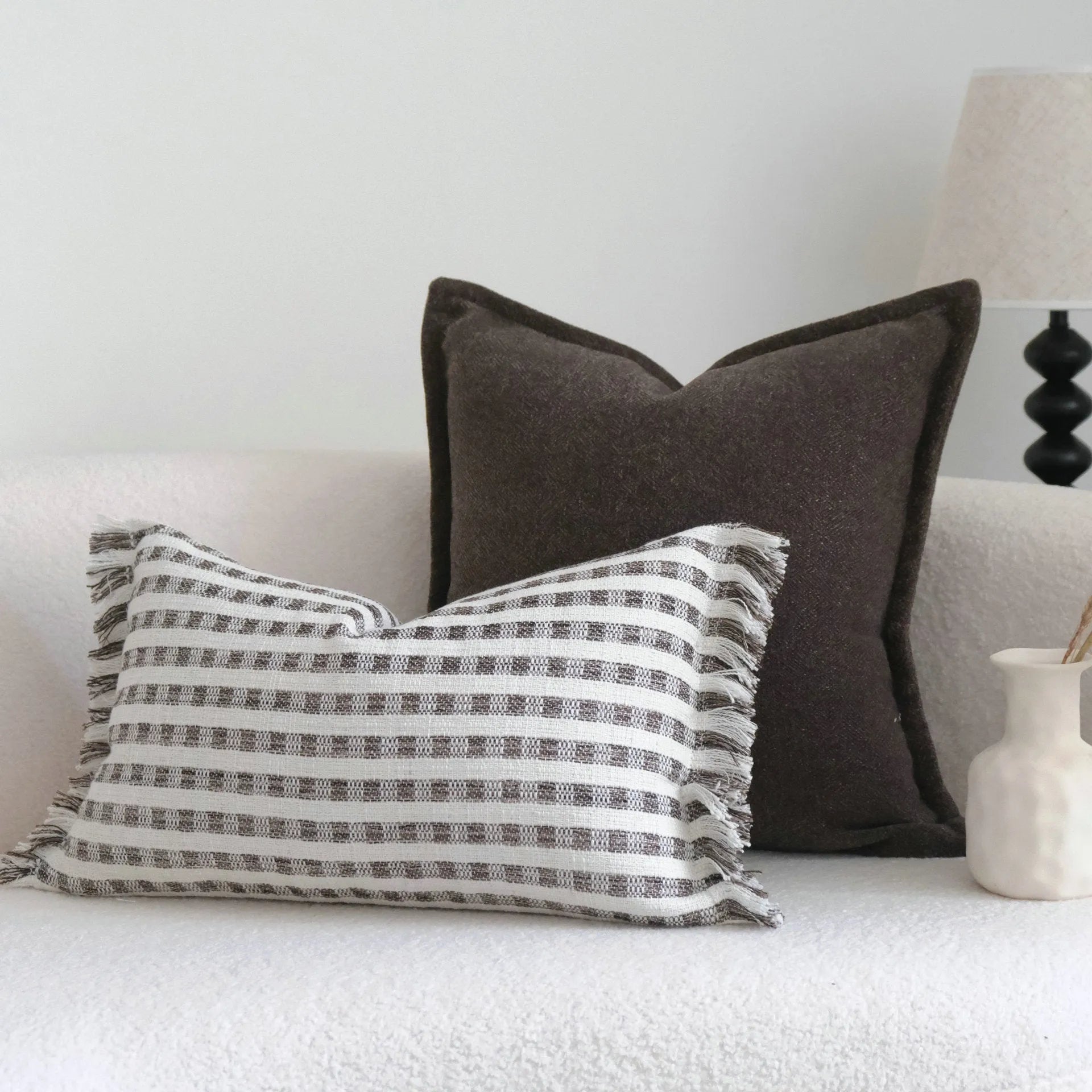 Coffee brown striped mid-century modern lumbar cushion on a grey sofa.