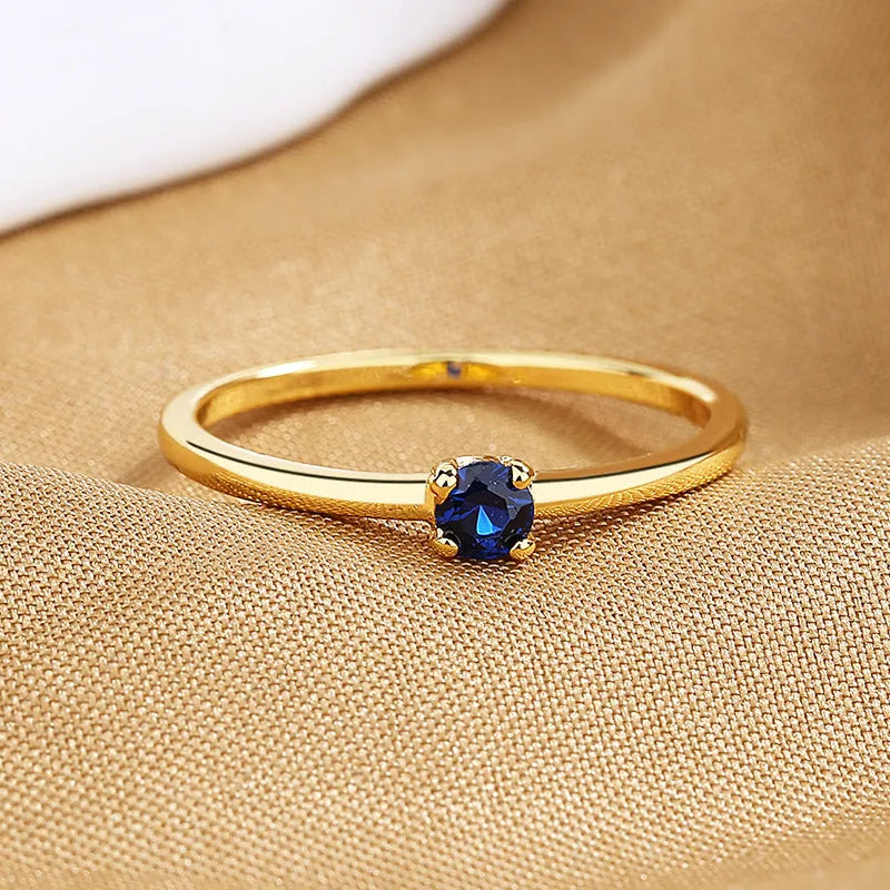 A women's fine copper circle ring with a single diamond, shown in blue, green, red, and white colour options.