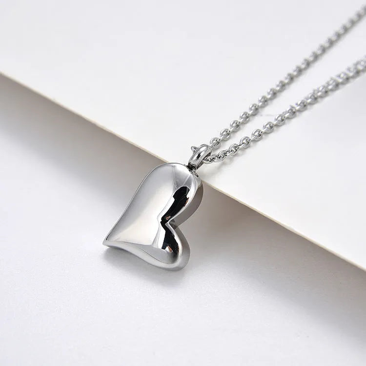 Silver curved peach heart pendant necklace on a stainless steel chain with an extension.