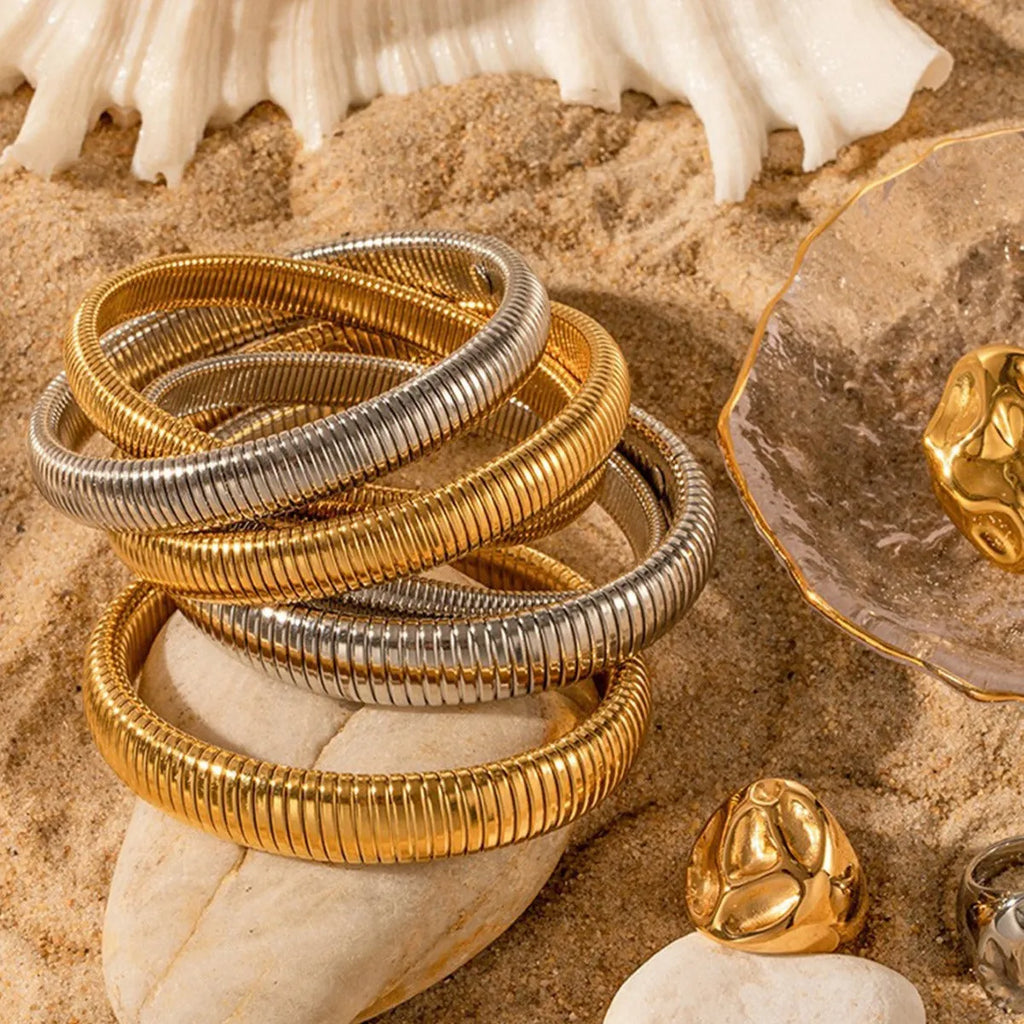 Women's titanium steel bracelet with vertical stripe ring design in gold plating, shown on a wrist.