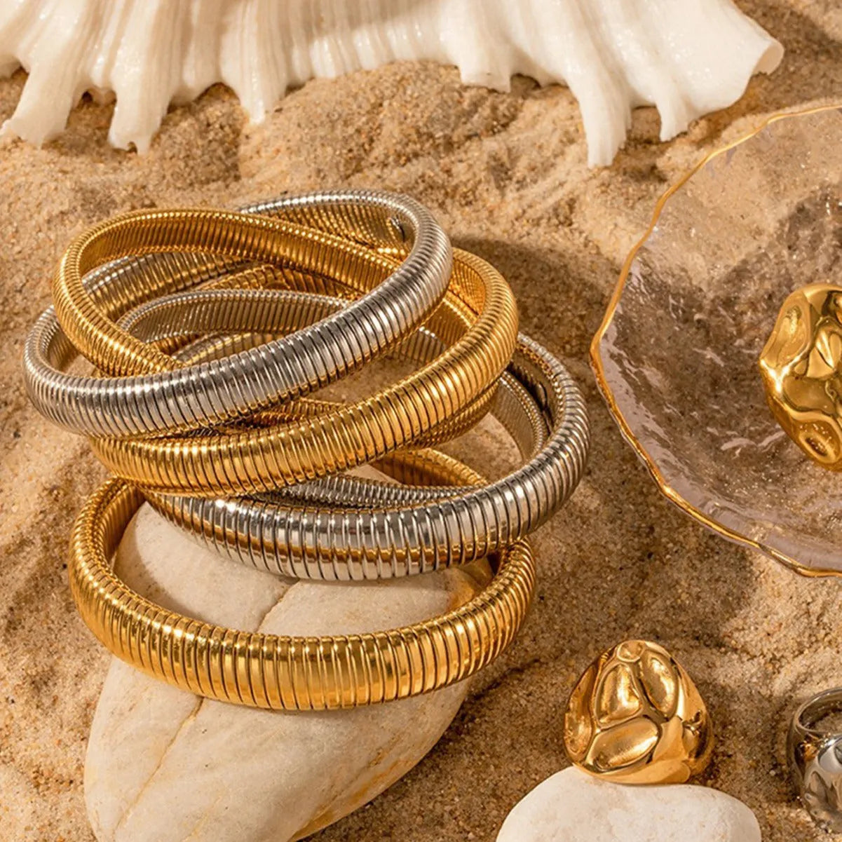 Women's titanium steel bracelet with vertical stripe ring design in gold plating, shown on a wrist.