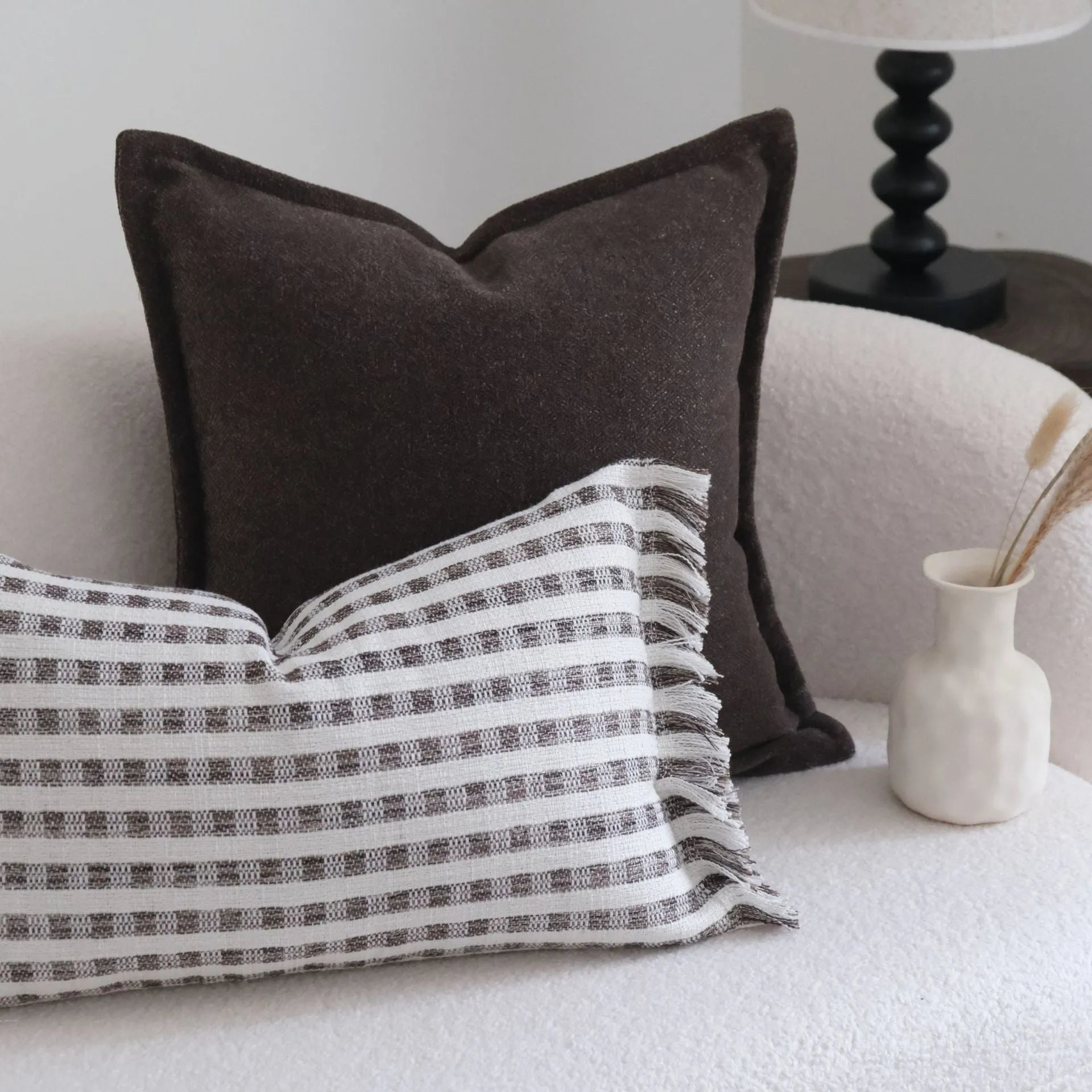 Coffee brown striped mid-century modern lumbar cushion on a grey sofa.
