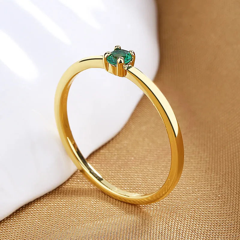 A women's fine copper circle ring with a single diamond, shown in blue, green, red, and white colour options.