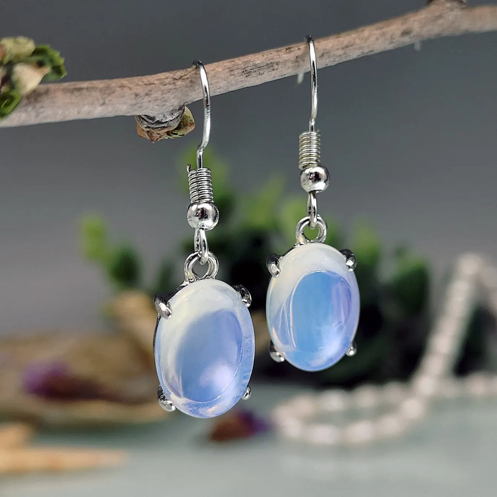 A pair of retro drop-shaped earrings with an opal moonstone colour and elliptical decorative elements.