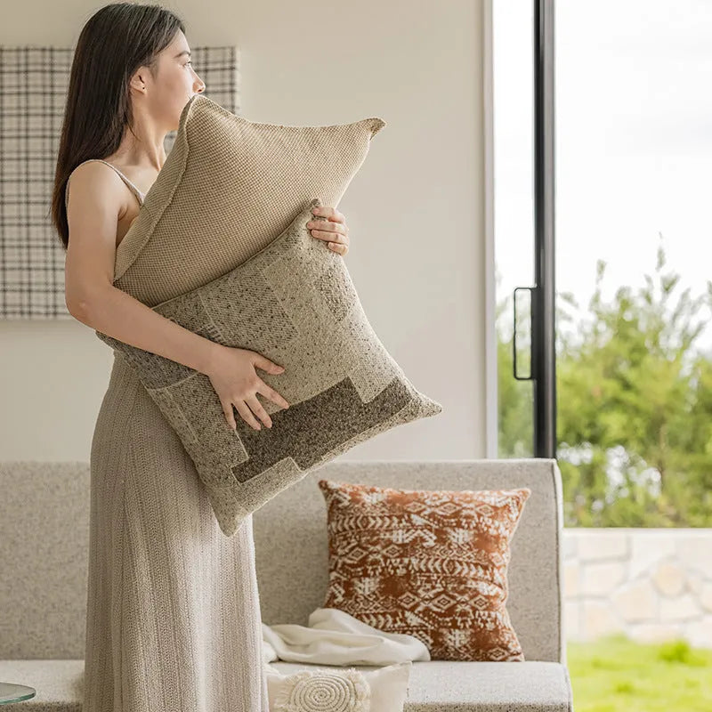 A square coreless decorative sofa cushion with an abstract geometric pattern in red and brown colours.
