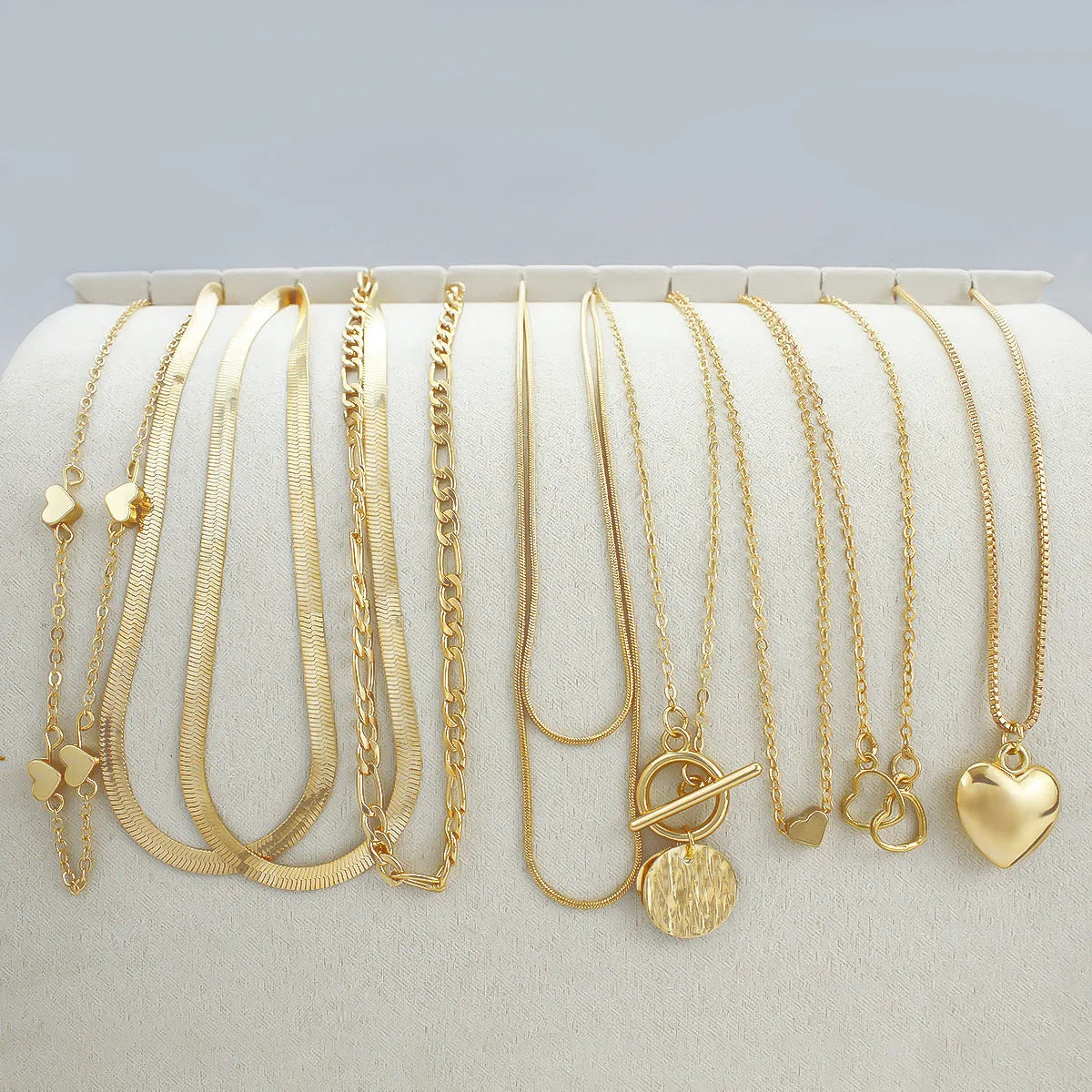 Set of ten gold-coloured women's necklaces with snake bones chains and alloy pendants.