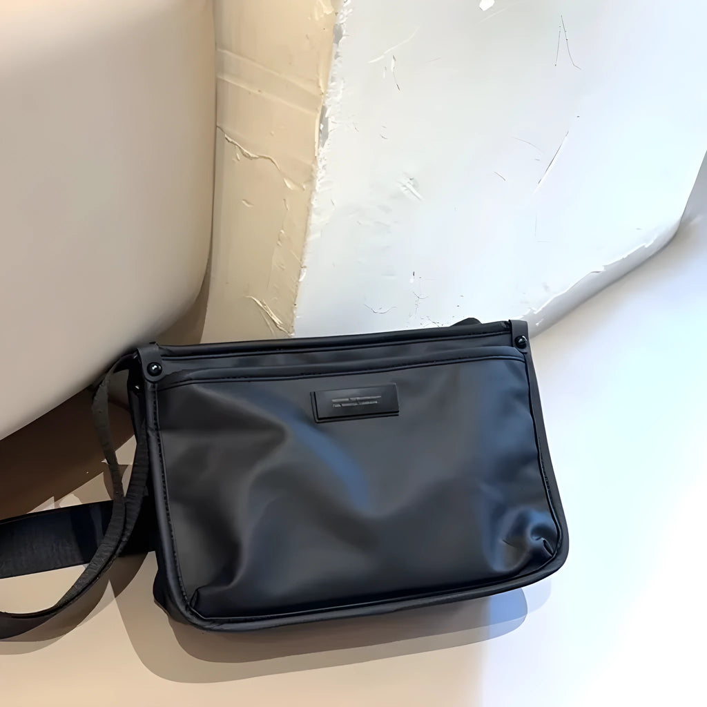 A small square crossbody bag in a cool retro style, made from textured Oxford cloth, shown on a person for scale.