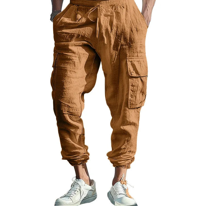 Man wearing loose khaki linen casual trousers with a drawstring waist and ankle-tied legs.