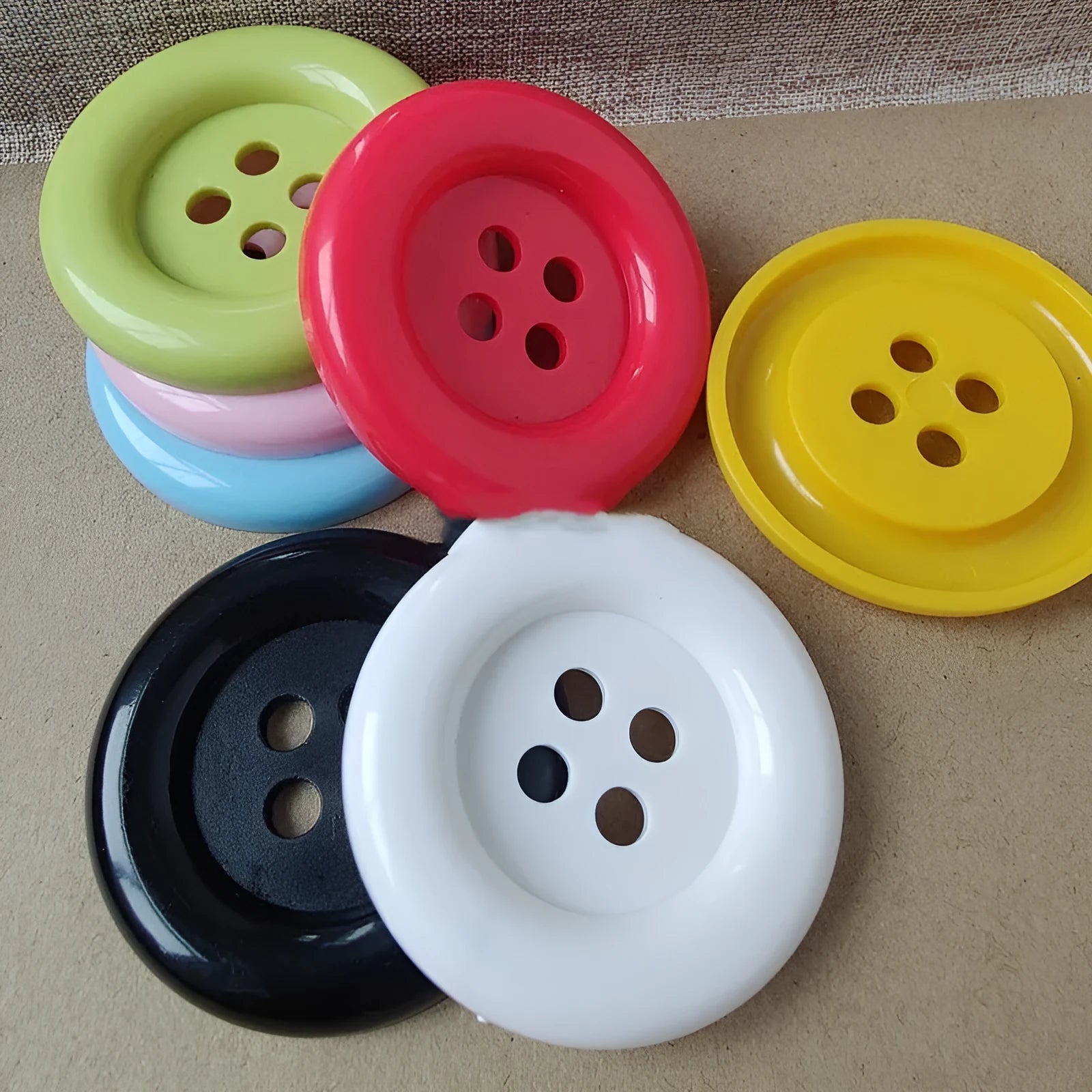 Assorted oversized round plastic buttons in black, white, red, blue and yellow on a white background.