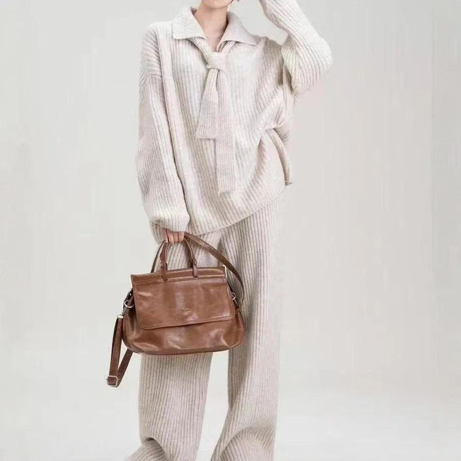Women's beige knitted top and matching trousers from a two-piece acrylic sweater suit set laid flat.