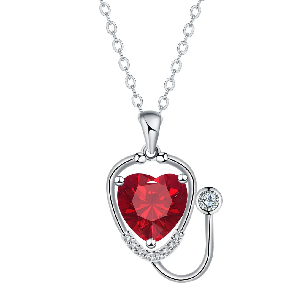 Red diamond stethoscope necklace with a wing and cross pendant on a chain.