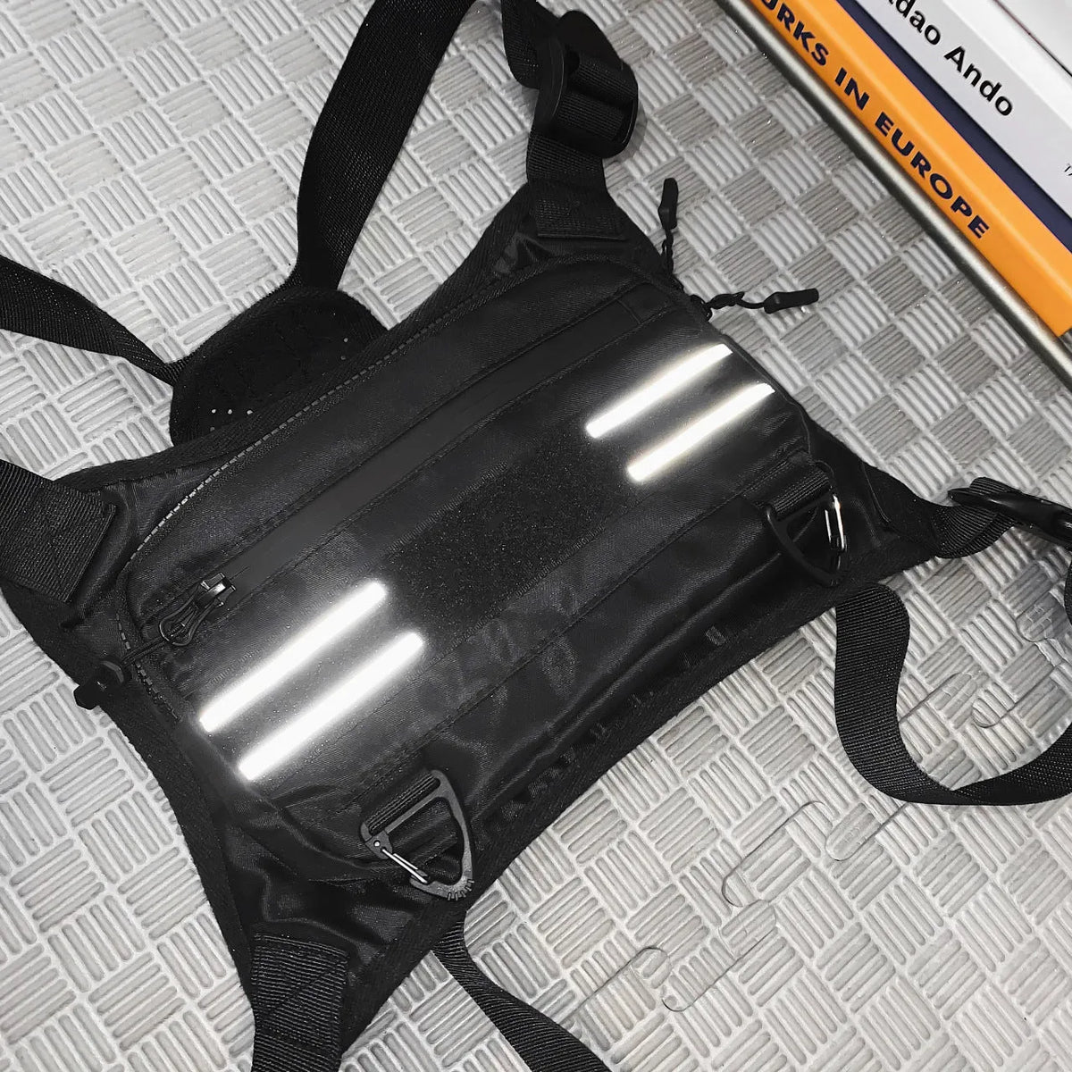 Black nylon tactical chest bag with reflective tooling style, solid colour, polyester lining and sewing thread detail