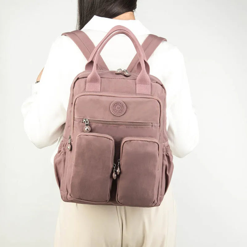 Waterproof nylon travel backpack in lotus root purple colour, showing multiple internal compartments and an external 3D pocket.