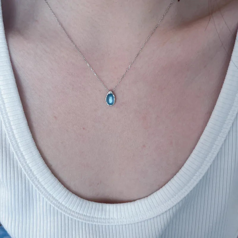 Navy blue water drop necklace with platinum accents on adjustable cross chain