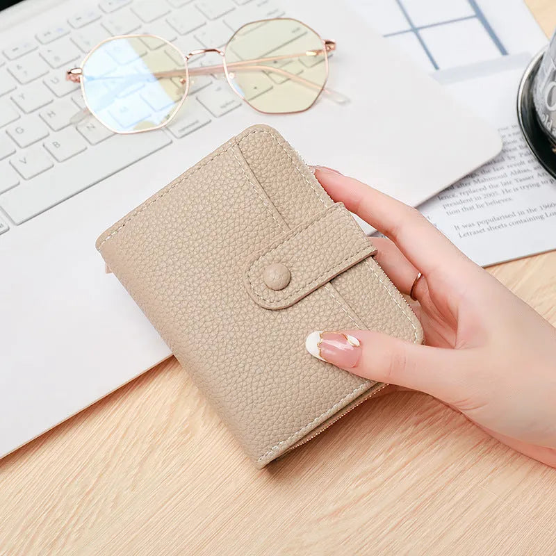 Beige ladies short wallet with a textured lychee pattern, shown in a two-fold open position.