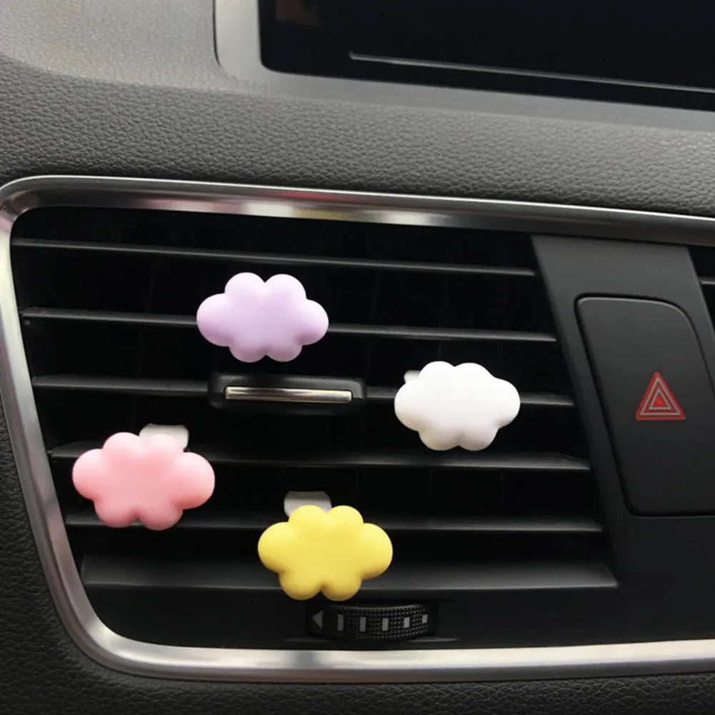 Small colourful resin car fragrance clip shown in multiple colours on a car air vent.