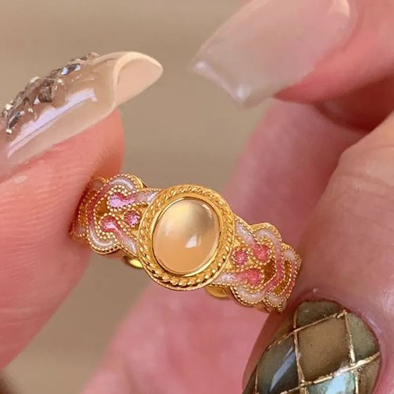 A pink crystal enamel ring with a geometric gold-plated copper band and an open mouth adjustable design.