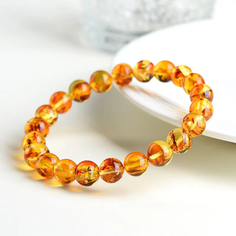 Natural yellow amber bracelet with piebald spots, showing geometric beads on a wrist.
