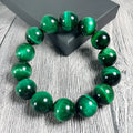 A natural green tiger eye stone bracelet with polished geometric beads on a wrist.