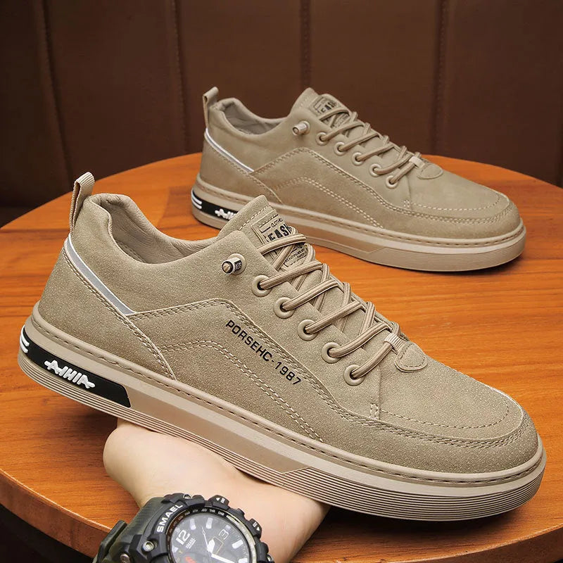 Men's low-top casual shoes in khaki with a round toe and rubber sole, shown on a work site background.