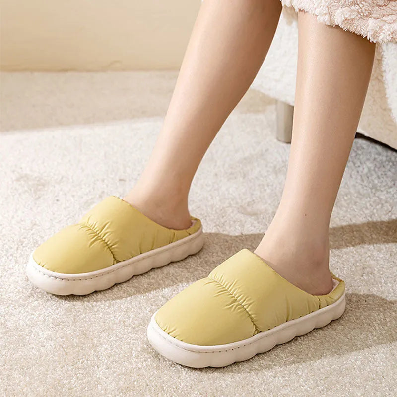 A pair of thick-soled indoor slippers with an artificial leather upper and soft plush lining, shown in a choice of colours.