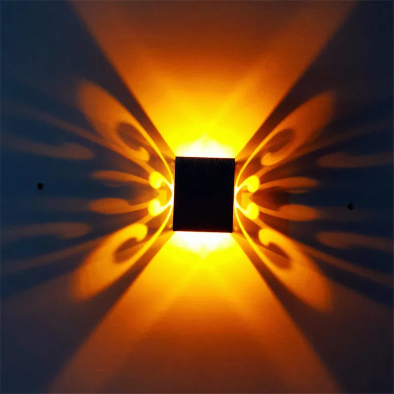Modern aluminium butterfly-shaped LED wall lamp on a white wall with remote control.