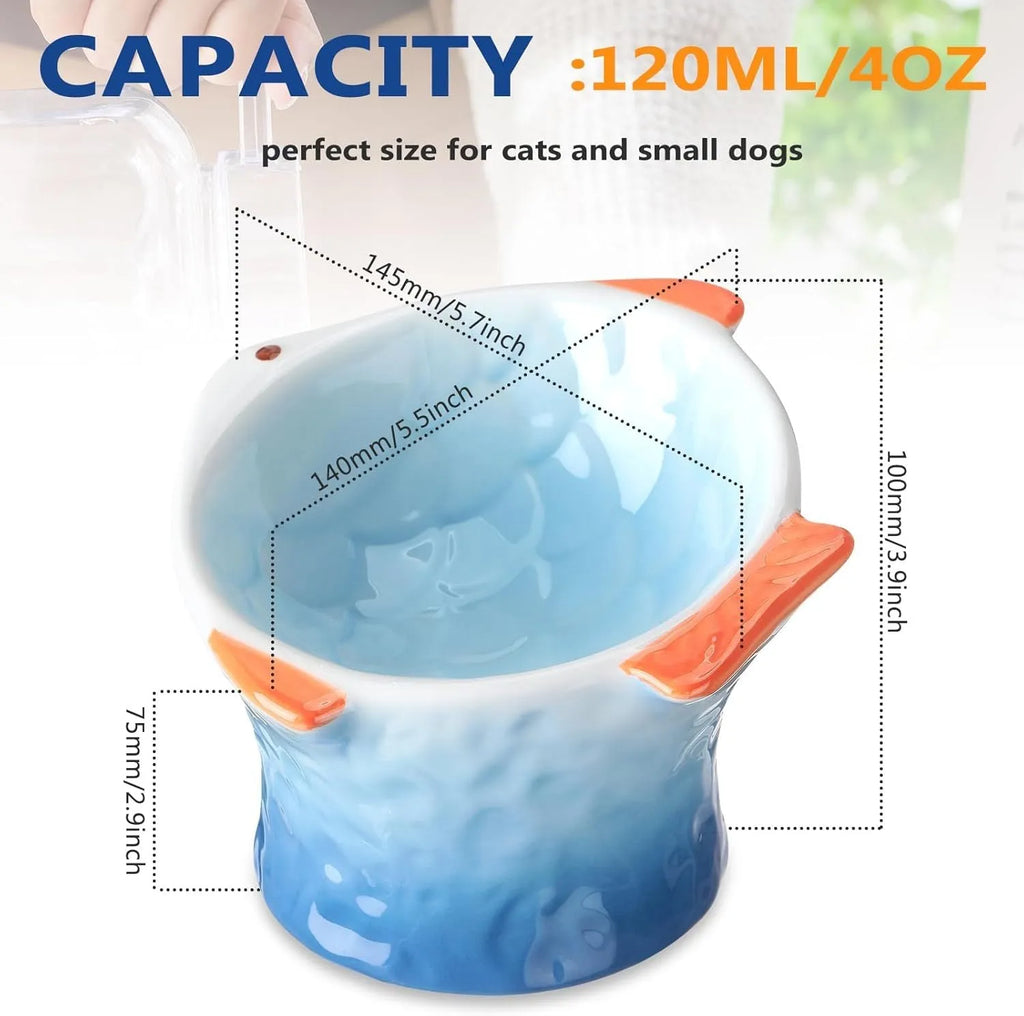 Blue fish-shaped ceramic cat bowl with tilted design and non-slip base on a wooden surface.