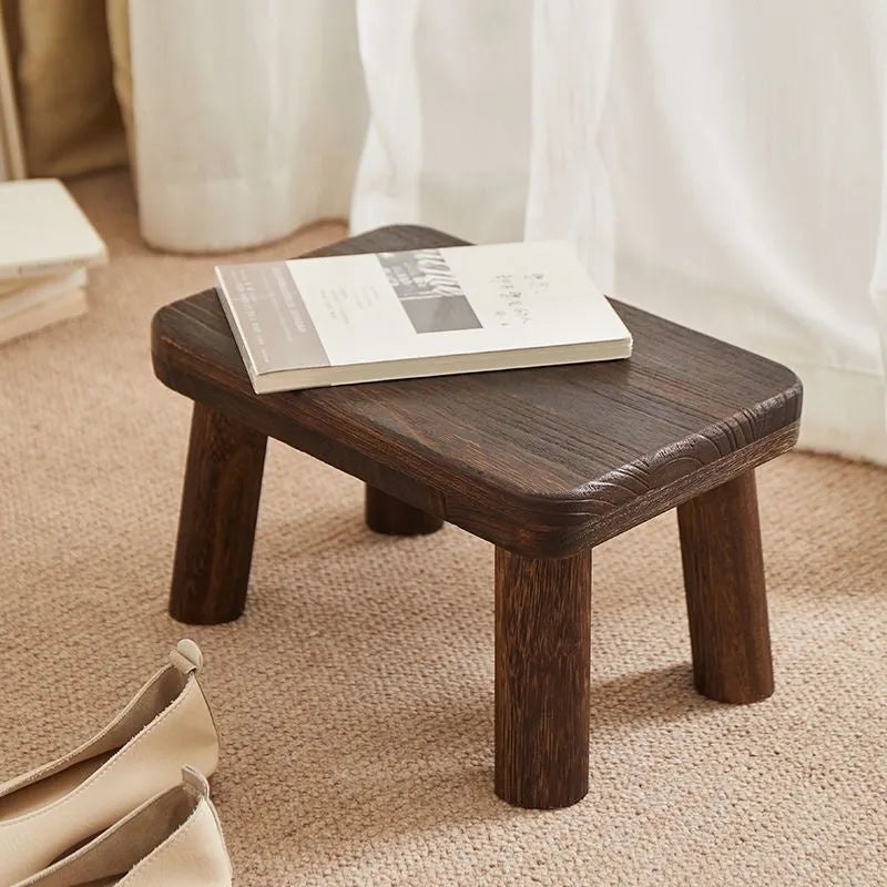 Solid wood distressed finish changing stool with bracket structure legs.