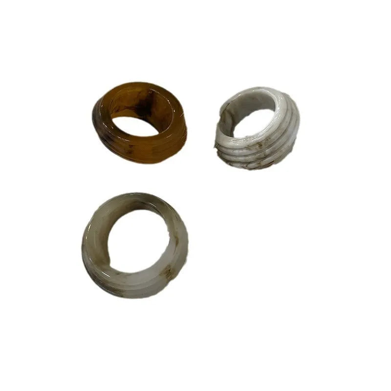 Chinese style irregular geometric wide resin ring in brown or white on a plain background.