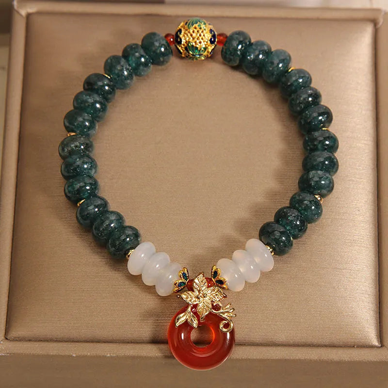 Close-up of a women's crystal bracelet with blue jade beads, red agate, and a silver peace buckle closure.