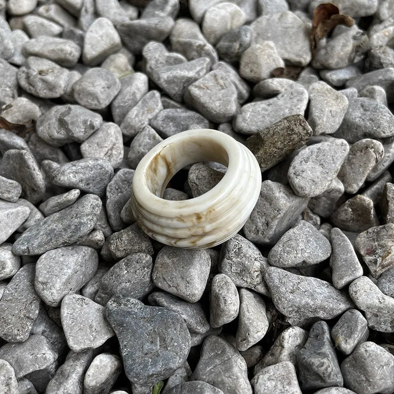 Chinese style irregular geometric wide resin ring in brown or white on a plain background.