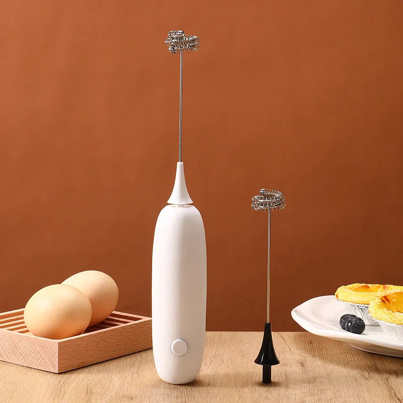 Black and white handheld electric milk frother and blender on a kitchen counter.