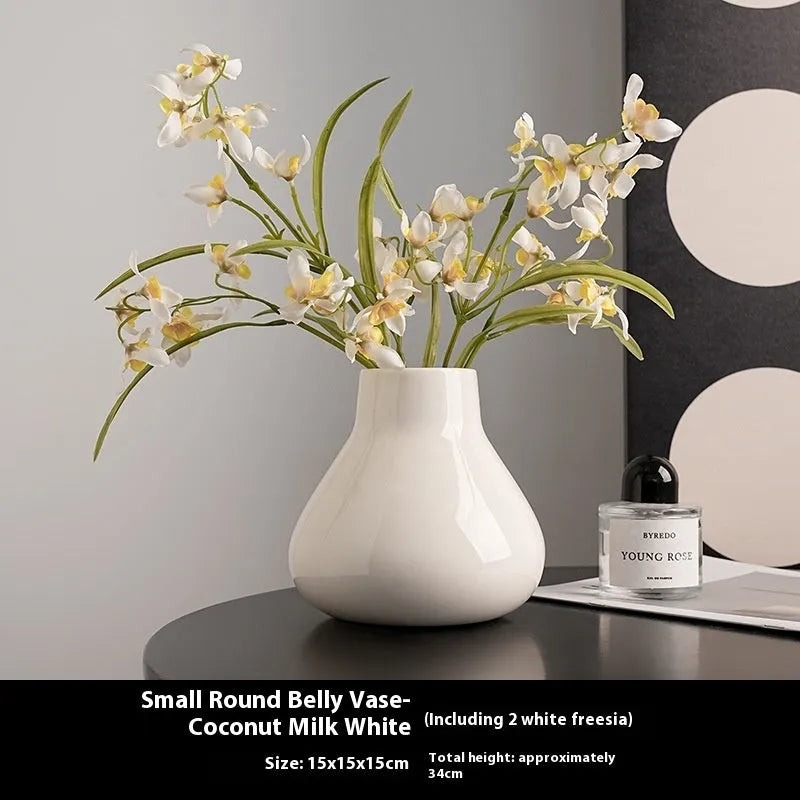 Black ceramic round belly vase with white orchid flowers on wooden shelf
