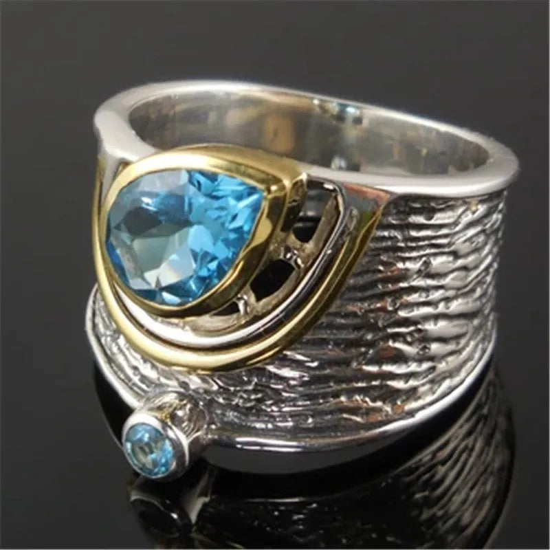 Blue zircon drop-shaped ring with Chinese style rhinestone inlay, shown on a finger.