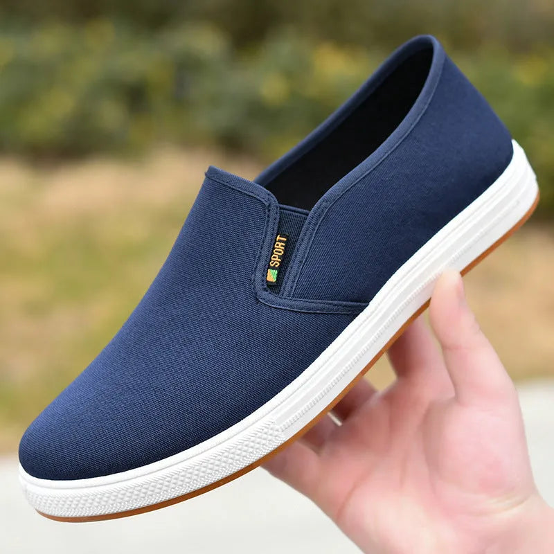 Men's black slip-on canvas trainers with round toe and low-top design on a white background