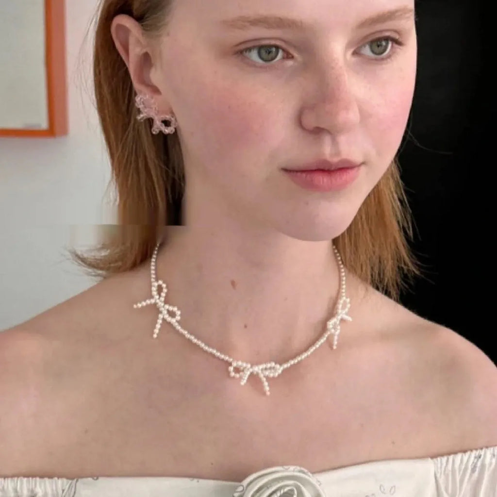 White geometric bow detail on an adjustable imitation pearl necklace for women, chain length 31-40cm.