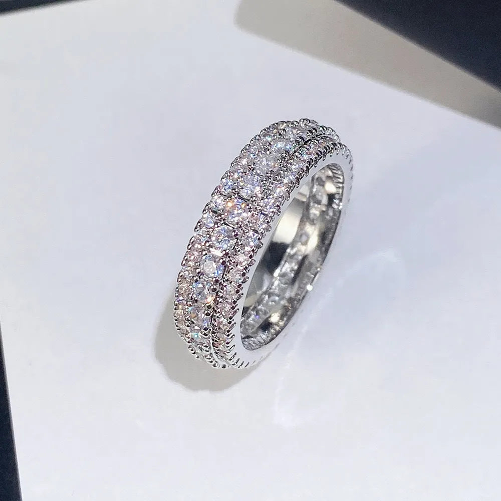 Geometric triangular zircon inlay ring in white gold finish on a finger.