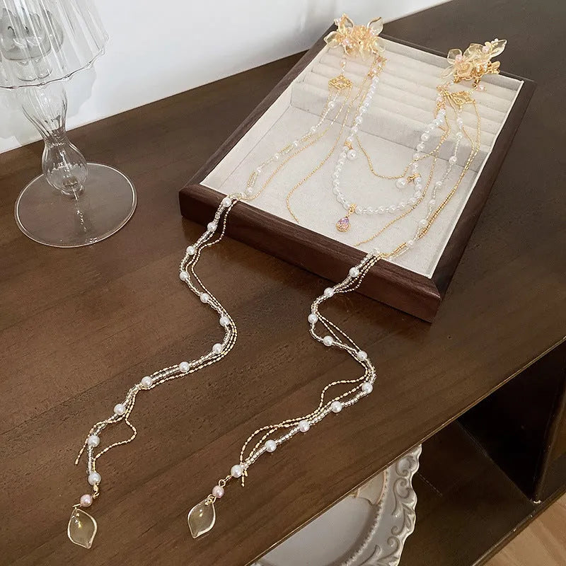 Gold grip acrylic hairpin with white pearl, clear diamond flower, and long beaded tassel decoration.