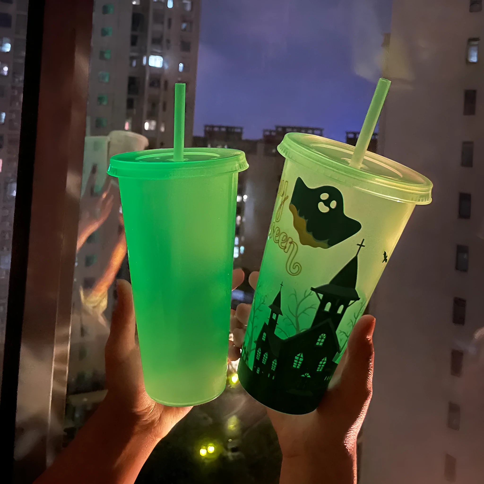 A tall, cylindrical Halloween-themed luminous plastic sippy cup with a straw, showing colour options.
