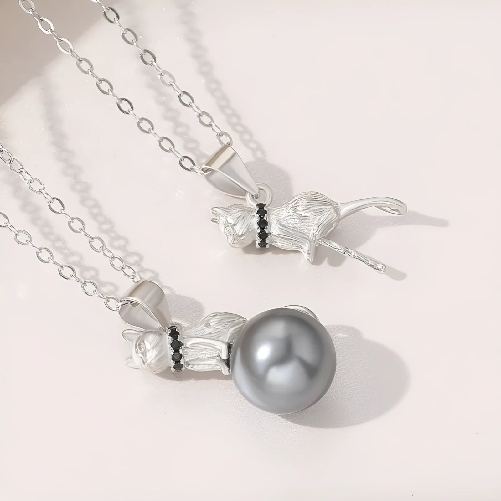 Close-up of a sterling silver cat pendant necklace on a clavicle, showing the electroplated finish.