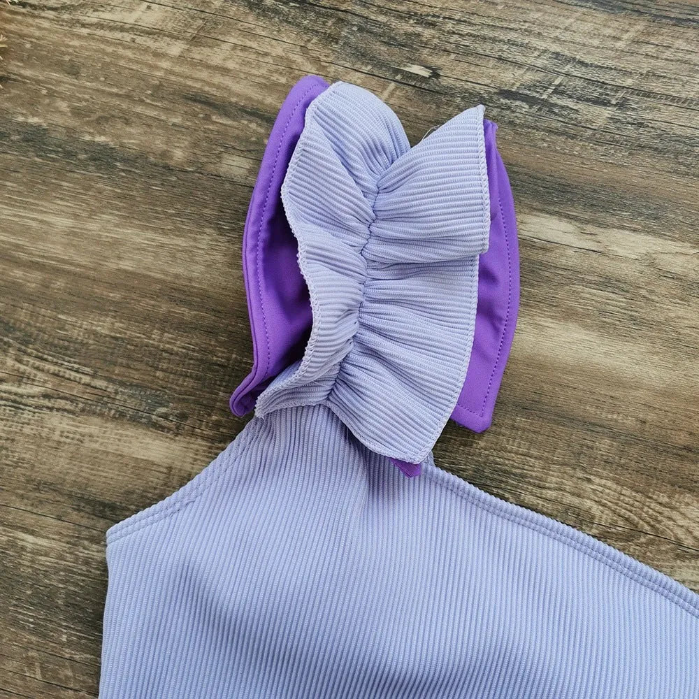 A blue women's one-piece swimsuit with a single suspender strap and a high-waist cut on a mannequin.